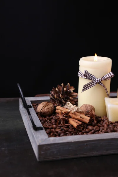 Candles on vintage tray with coffee grains and spices, bumps on wooden table, on dark background — Stock Photo, Image