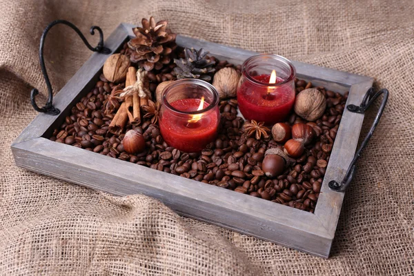 Candles on vintage tray with coffee grains and spices, bumps on sackcloth background — Stock Photo, Image