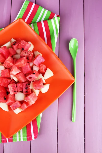 Wassermelonenscheiben in orangefarbenem Teller auf Serviette auf hölzernem Hintergrund — Stockfoto