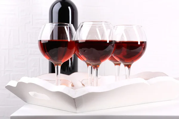 Brýle a víno láhev na tác v místnosti — Stock fotografie