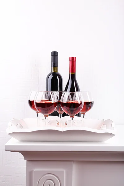 Glasses and wine bottle on tray in room — Stock Photo, Image