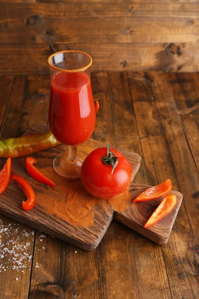 Glas leckeren Tomatensaft und Pfeffer auf Holztisch — Stockfoto