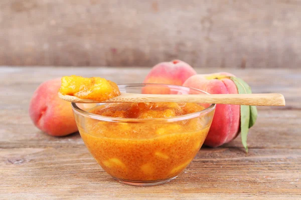 Вкусный персиковый джем со свежими персиками на деревянном столе — стоковое фото