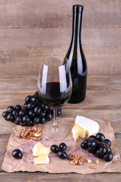 Kaunis asetelma viinillä, juustolla ja kypsillä rypäleillä puupohjalla — kuvapankkivalokuva