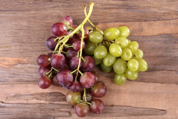 Bunches of different kinds of grapes on wooden background — Stock Photo, Image