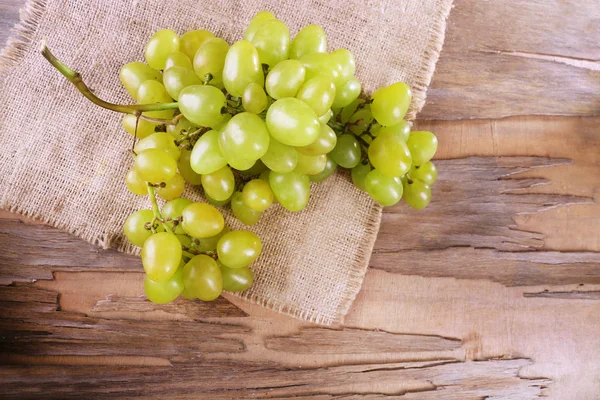 Bunch of ripe grape on napkin on wooden table on wooden wall background — Stock Photo, Image