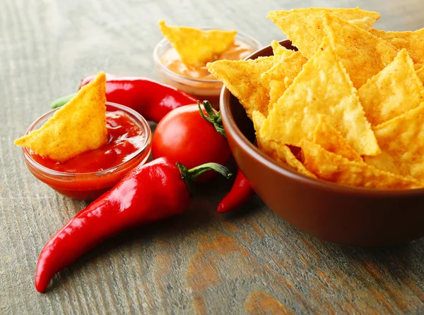 Tasty nachos, red tomatoes and chili pepper in color bowl on wooden background — Stock Photo, Image