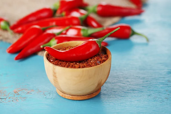 Milled red chili pepper in bowl on wooden background — Stock Photo, Image