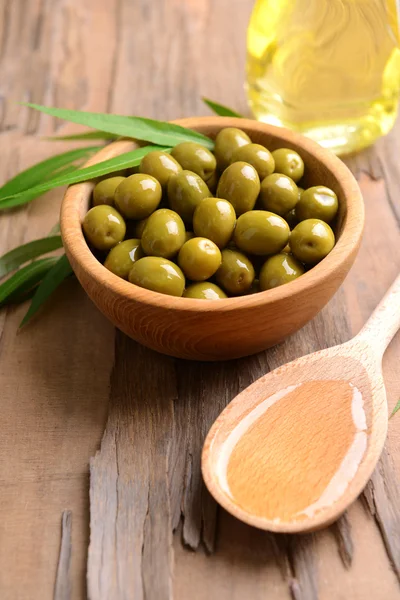 Groene olijven in kom met bladeren op tabel close-up — Stockfoto