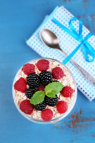 Healthy breakfast - yogurt with  fresh fruit, berries and muesli served in glass jar, on color wooden background — Stock Photo, Image