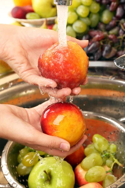 Le mani di donna che lavano pesche e altri frutti in colabrodo in lavandino — Foto Stock