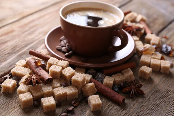 Brunt socker, kryddor och kopp kaffe på trä bakgrund — Stockfoto