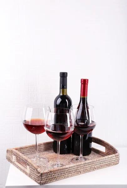 Glasses and wine bottle on tray in room — Stock Photo, Image