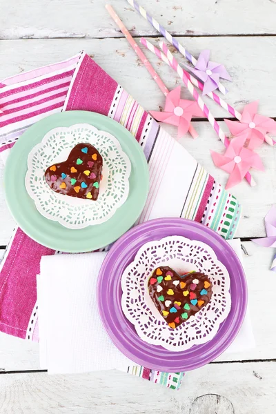 Deliziose torte arcobaleno su piatti, su sfondo di legno a colori — Foto Stock