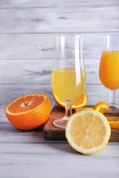 Склянки соку зі свіжими фруктами на сірому дерев'яному столі — стокове фото