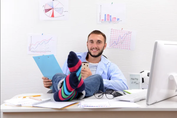 Selbstbewusster Geschäftsmann hält seine Beine in lustigen Socken auf dem Schreibtisch — Stockfoto