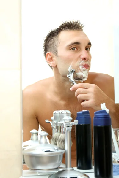 Young man shaving his beard in bathroom — Stock Photo, Image