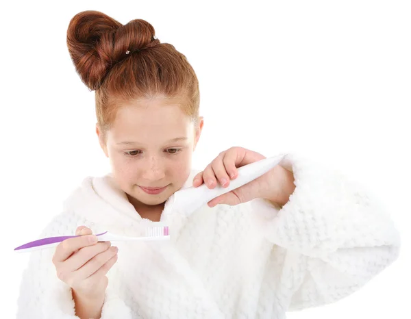 Hermosa niña en albornoz sosteniendo cepillo de dientes y pasta de dientes aislados en blanco —  Fotos de Stock