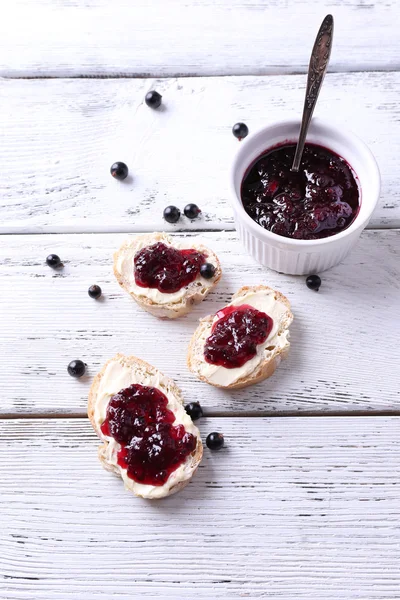 Pane fresco con burro fatto in casa e marmellata di ribes nero su sfondo di legno — Foto Stock