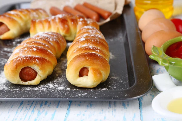 Rollos de salchicha al horno en bandeja en primer plano de la mesa —  Fotos de Stock