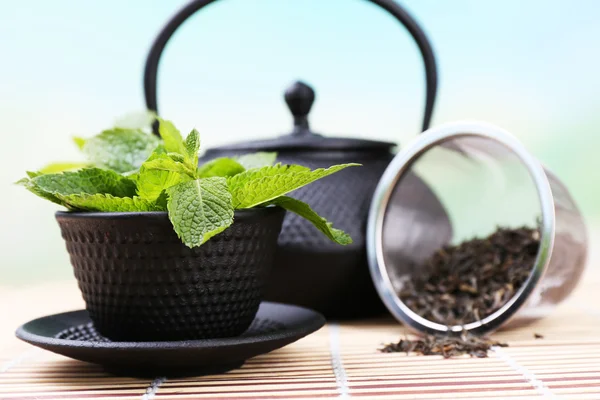 Théière traditionnelle chinoise avec des feuilles de menthe fraîche sur table en bois, sur fond lumineux — Photo