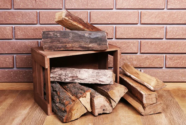 Wooden box of firewood on floor on brick background — Stock Photo, Image