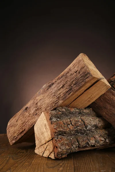 Brennholzstapel auf dem Fußboden vor dunklem Hintergrund — Stockfoto