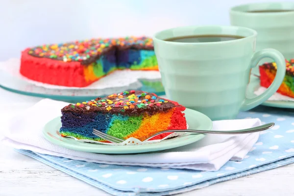 Deliziosa torta arcobaleno sul piatto, sul tavolo, su sfondo chiaro — Foto Stock