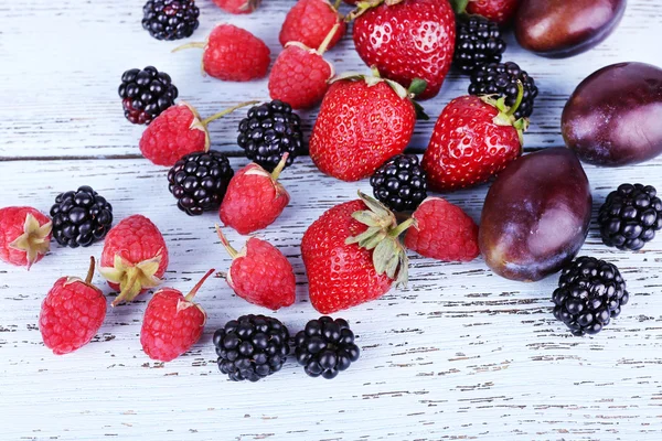 Различные ягоды и сливы на деревянном столе крупным планом — стоковое фото