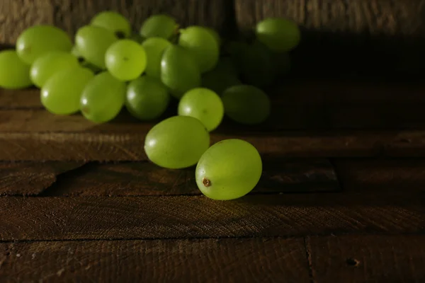 Uva verde sobre mesa de madera sobre fondo de madera —  Fotos de Stock