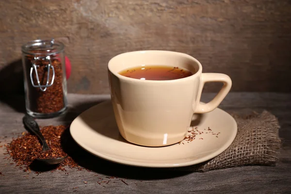 Чашка вкусного чая с ройбосом, на деревянном столе — стоковое фото
