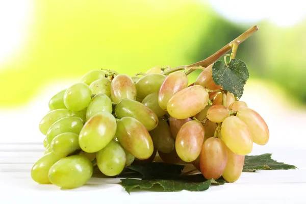 Bando de uvas maduras em mesa de madeira sobre fundo natural — Fotografia de Stock