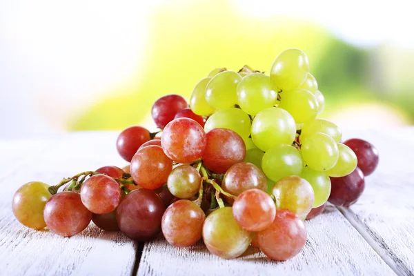 Bunches of ripe grapes on wooden table on natural background — Stock Photo, Image