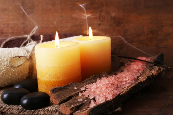 Piedras de spa con velas y sal marina sobre fondo de madera —  Fotos de Stock