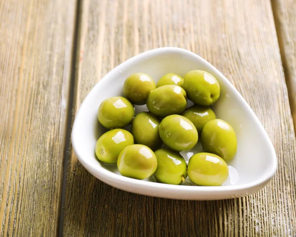 Aceitunas verdes en tazón en primer plano de la mesa — Foto de Stock