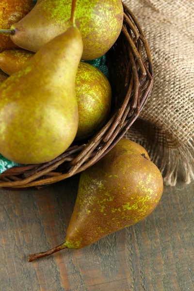 Ripe pears in wicker basket, on wooden background — Stock Photo, Image