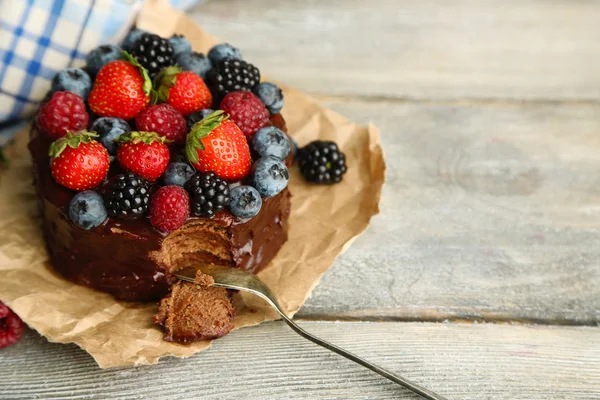 Chutný čokoládový dort s různými plody na dřevěný stůl — Stock fotografie