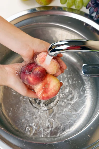 Hands washing peaches — Stock Photo, Image