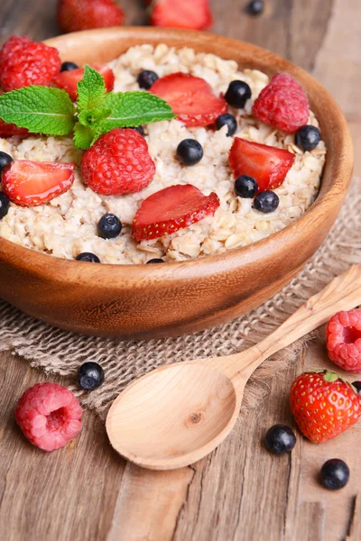 Tasty oatmeal with berries on table close-up