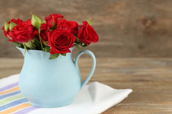 Bouquet de roses rouges en vase sur fond bois — Photo