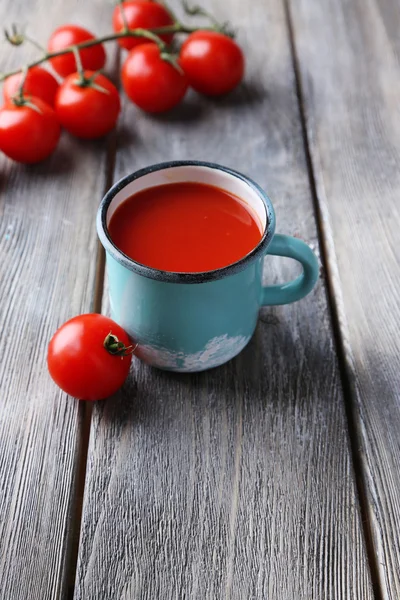 Zelfgemaakte tomatensap in kleur mok en verse tomaten op houten achtergrond — Stockfoto