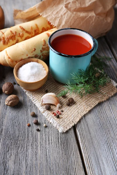 Hausgemachter Tomatensaft in farbigem Becher, Brotstangen, Gewürzen und frischen Tomaten auf Holzuntergrund — Stockfoto