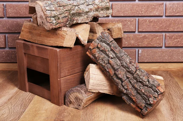 Caja de madera de leña en el suelo sobre fondo de ladrillo — Foto de Stock