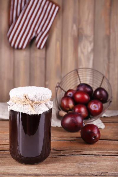 Tasty plum jam in jar and plums on wooden table close-up — Stock Photo, Image