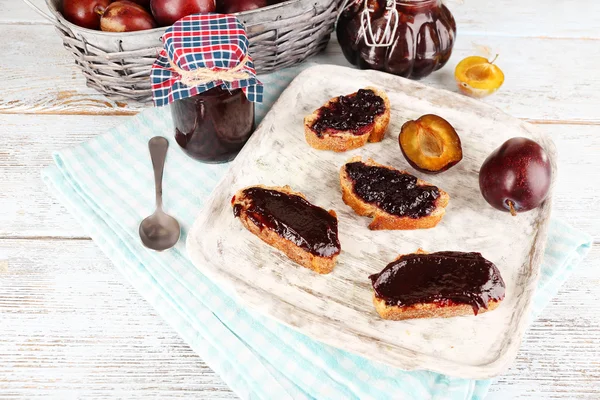 Bread with plum jam and plums on wooden table — Stock Photo, Image