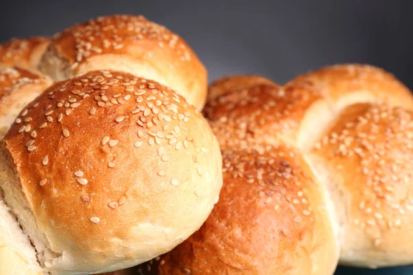 Tasty buns with sesame on color wooden table, on gray background — Stock Photo, Image