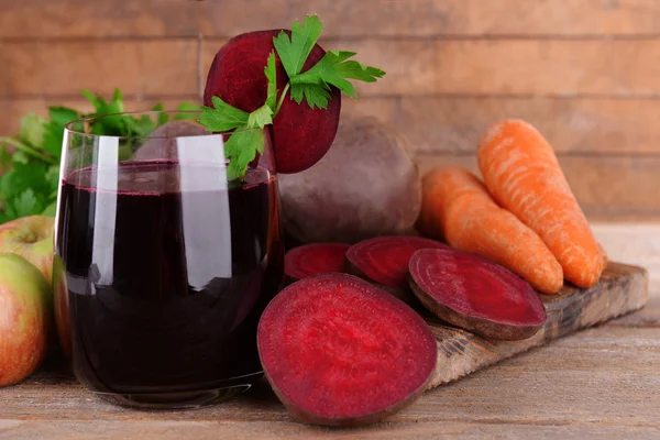 Glas på färska betor juice och grönsaker på trä bakgrund — Stockfoto