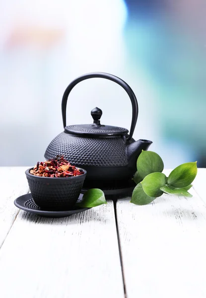 Black teapot, bowl and tea on color wooden table, on bright background — Stock Photo, Image