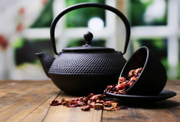 Musta teekannu, kulho ja hibiscus-tee väripuupöydällä, kirkkaalla taustalla — kuvapankkivalokuva