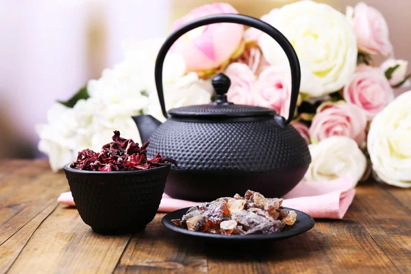 Black teapot, bowl and hibiscus tea on color wooden table, on bright background — Stock Photo, Image